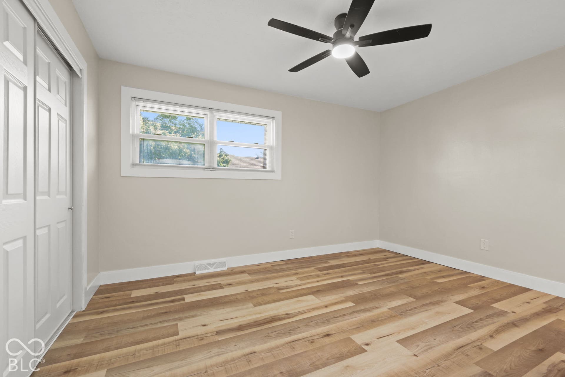 Wood-finish flooring, neutral wall tones, and a ceiling fan with integrated lighting
