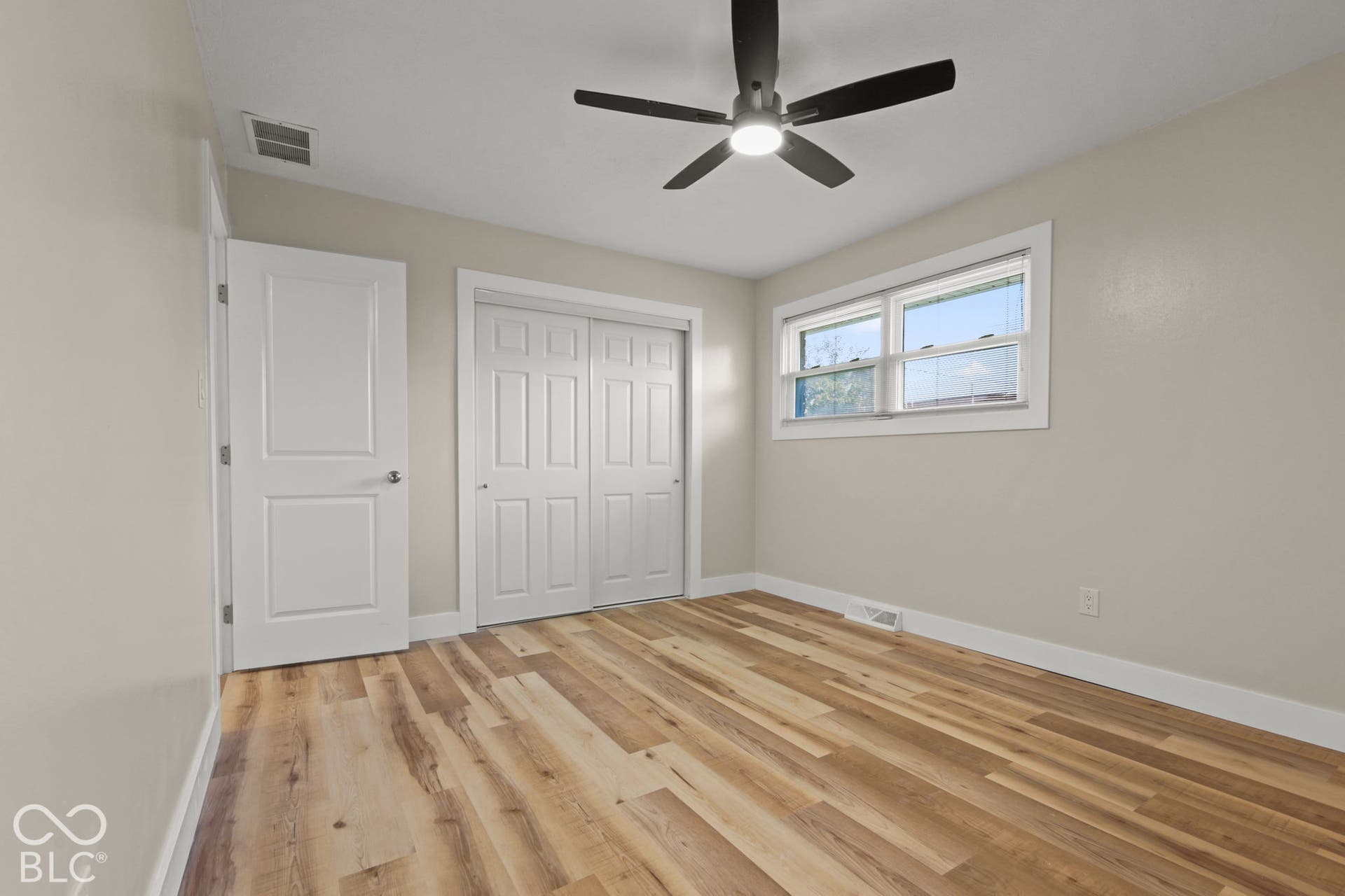 Wood-finish flooring, white paneled doors, and a ceiling fan with integrated lighting
