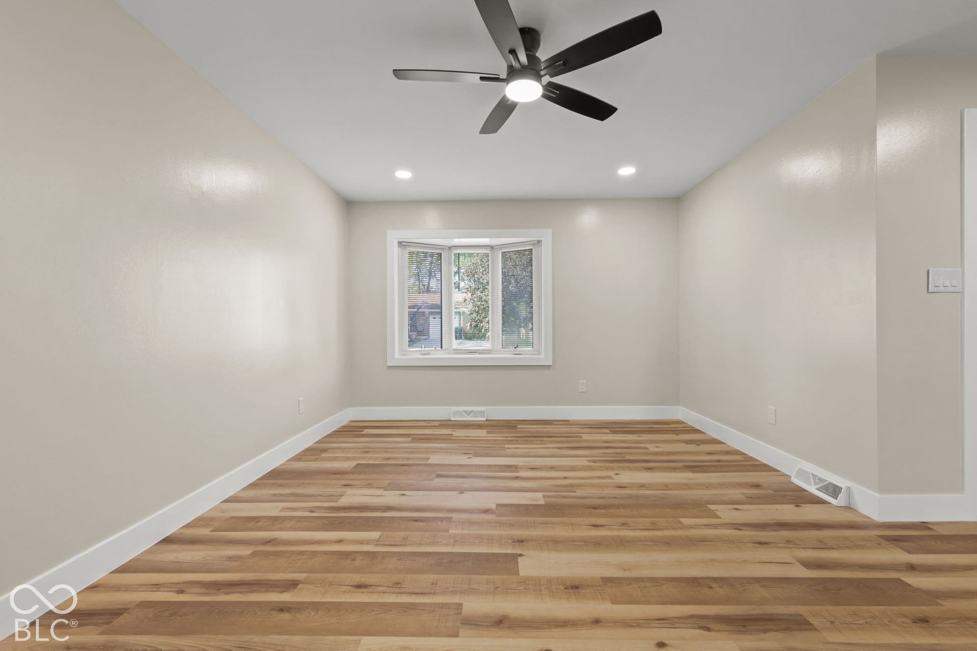 Wood-finish flooring, bay window, recessed lighting, ceiling fan, and crisp white trim