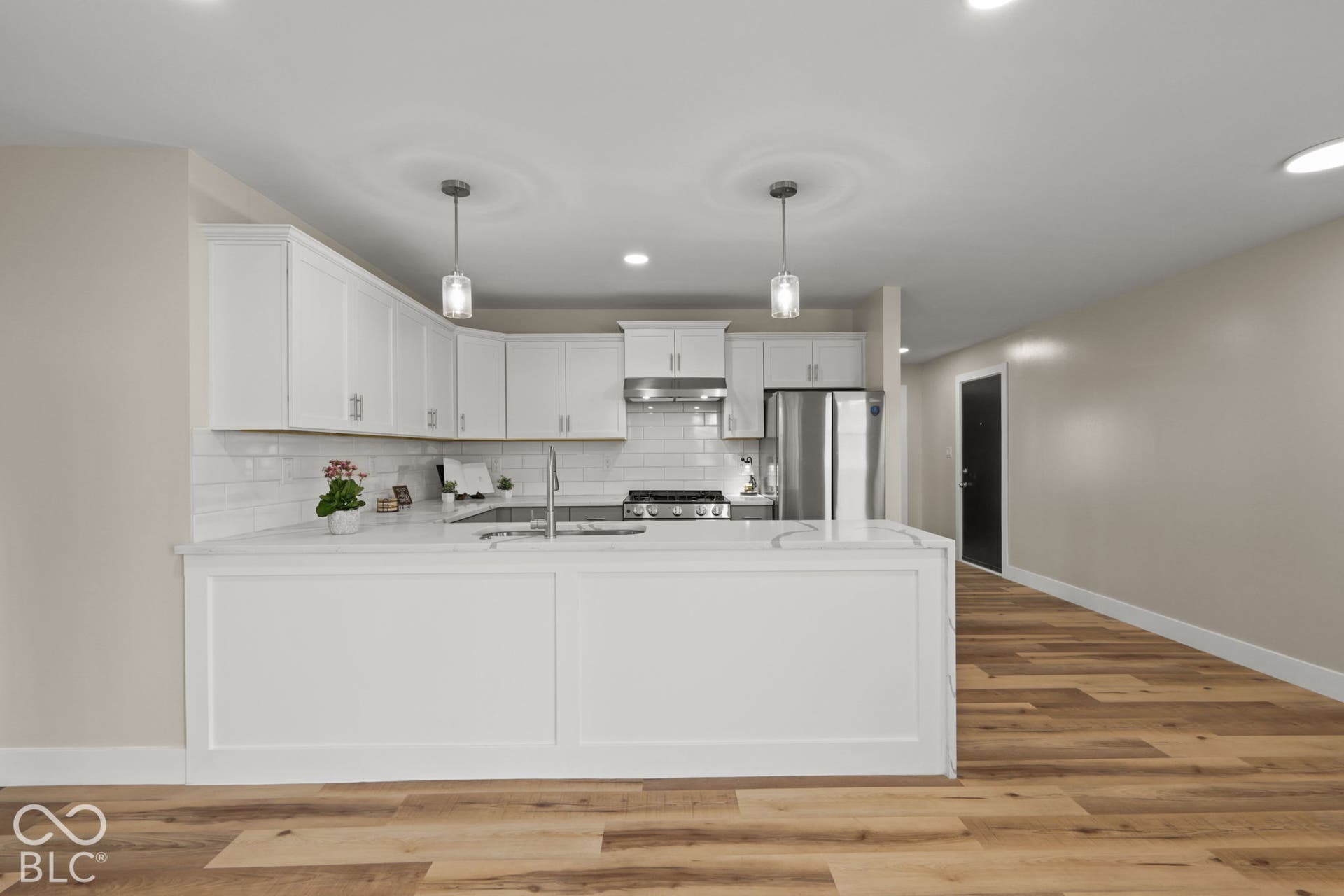 Kitchen featuring white cabinetry, stainless steel appliances, a subway tile backsplash, and light wood-finish flooring