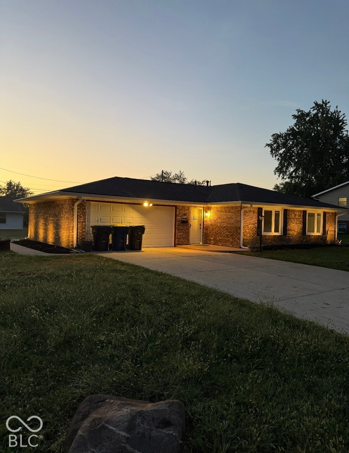 Brick exterior, attached garage, driveway, and front yard