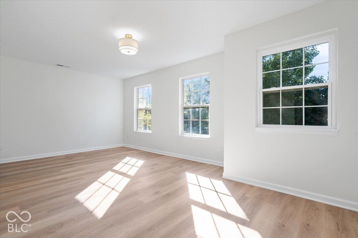 11780 Copper Mines Way, Fishers, IN 46038 Three windows, wood-finish flooring, white walls, and a semi-flush mount ceiling light fixture