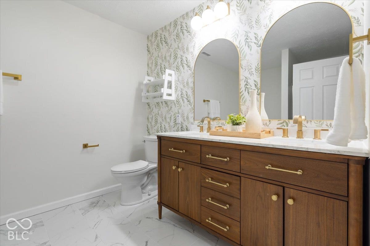 11780 Copper Mines Way, Fishers, IN 46038 Dual wood-finish vanity with gold-tone hardware, white countertop, and dual arched mirrors
