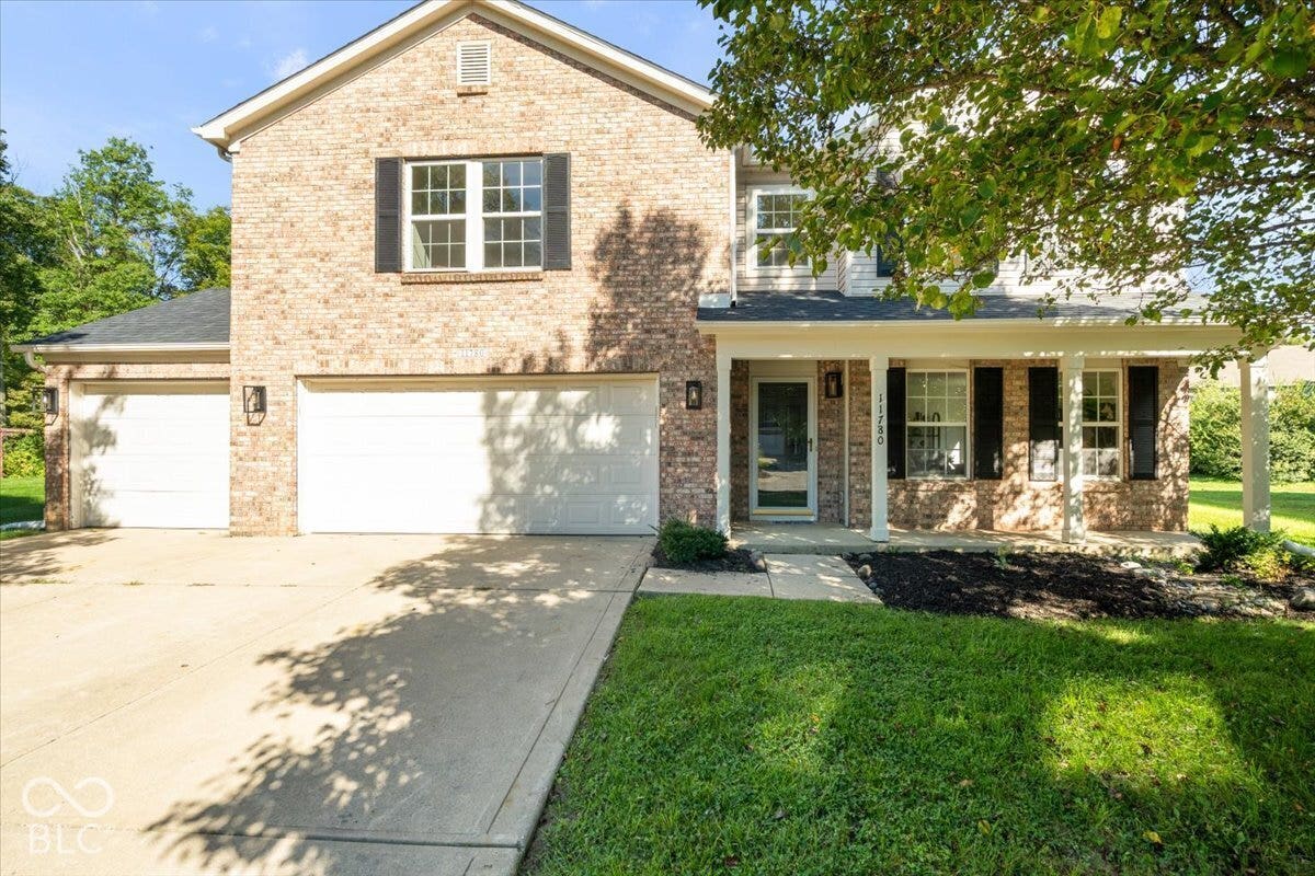 11780 Copper Mines Way, Fishers, IN 46038 Brick facade with a covered porch, multiple garages, and a concrete driveway