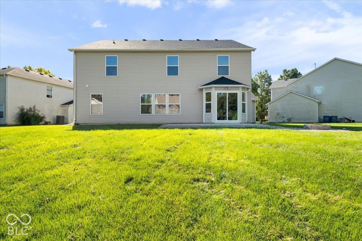11780 Copper Mines Way, Fishers, IN 46038 Expansive green lawn with a concrete patio, bay window, multiple windows, and light-colored siding