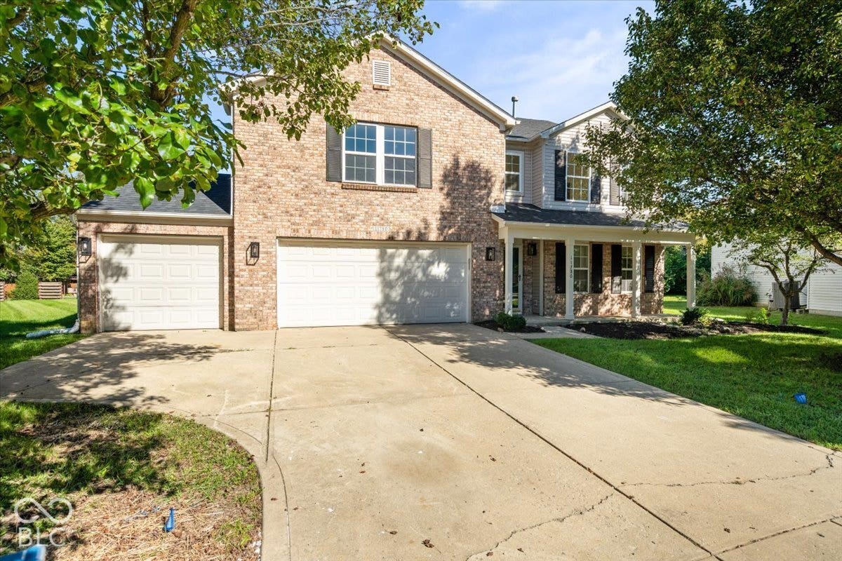 11780 Copper Mines Way, Fishers, IN 46038 Brick and siding facade with a covered front porch, dual garage doors, and a concrete driveway