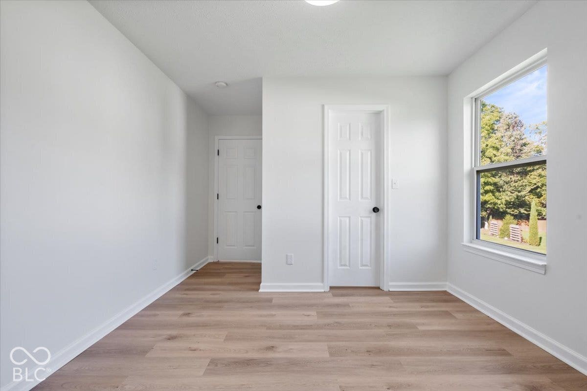 11780 Copper Mines Way, Fishers, IN 46038 Light wood-finish flooring, white walls, white trim, and a window with a natural backdrop