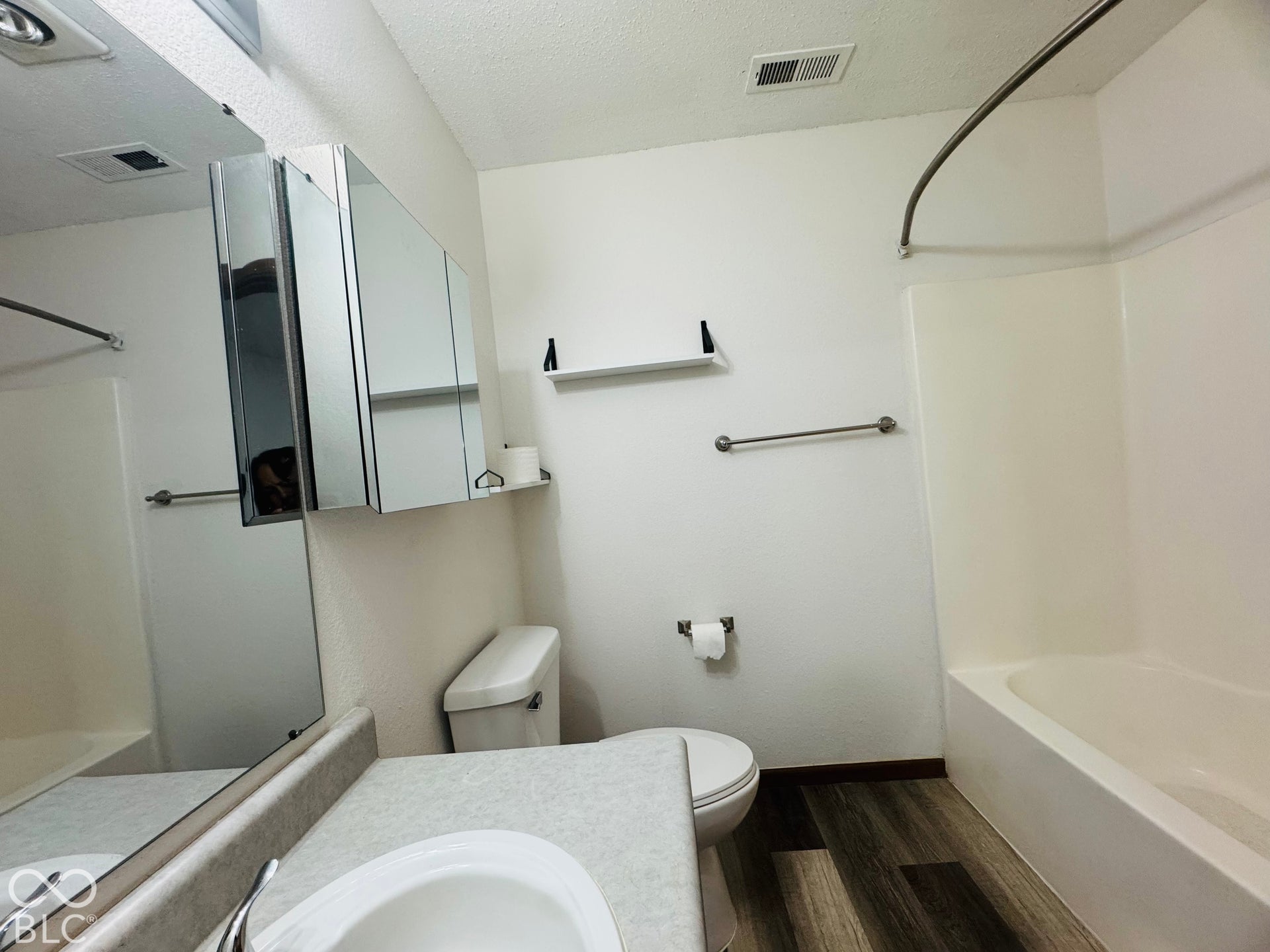 Bathroom with a single vanity, wood-finish flooring, a white bathtub, and a mirrored medicine cabinet