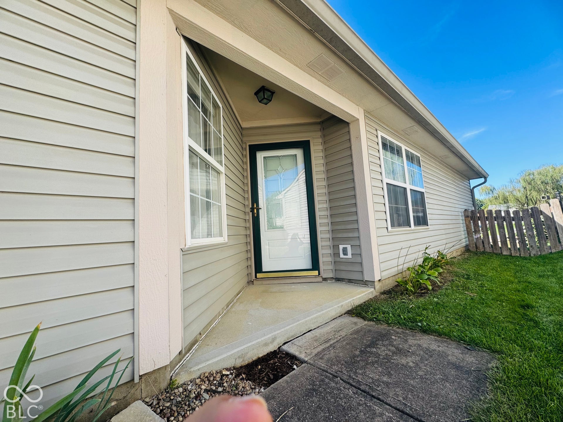 Entryway featuring a covered concrete porch, white framed windows, exterior wall light, and horizontal siding