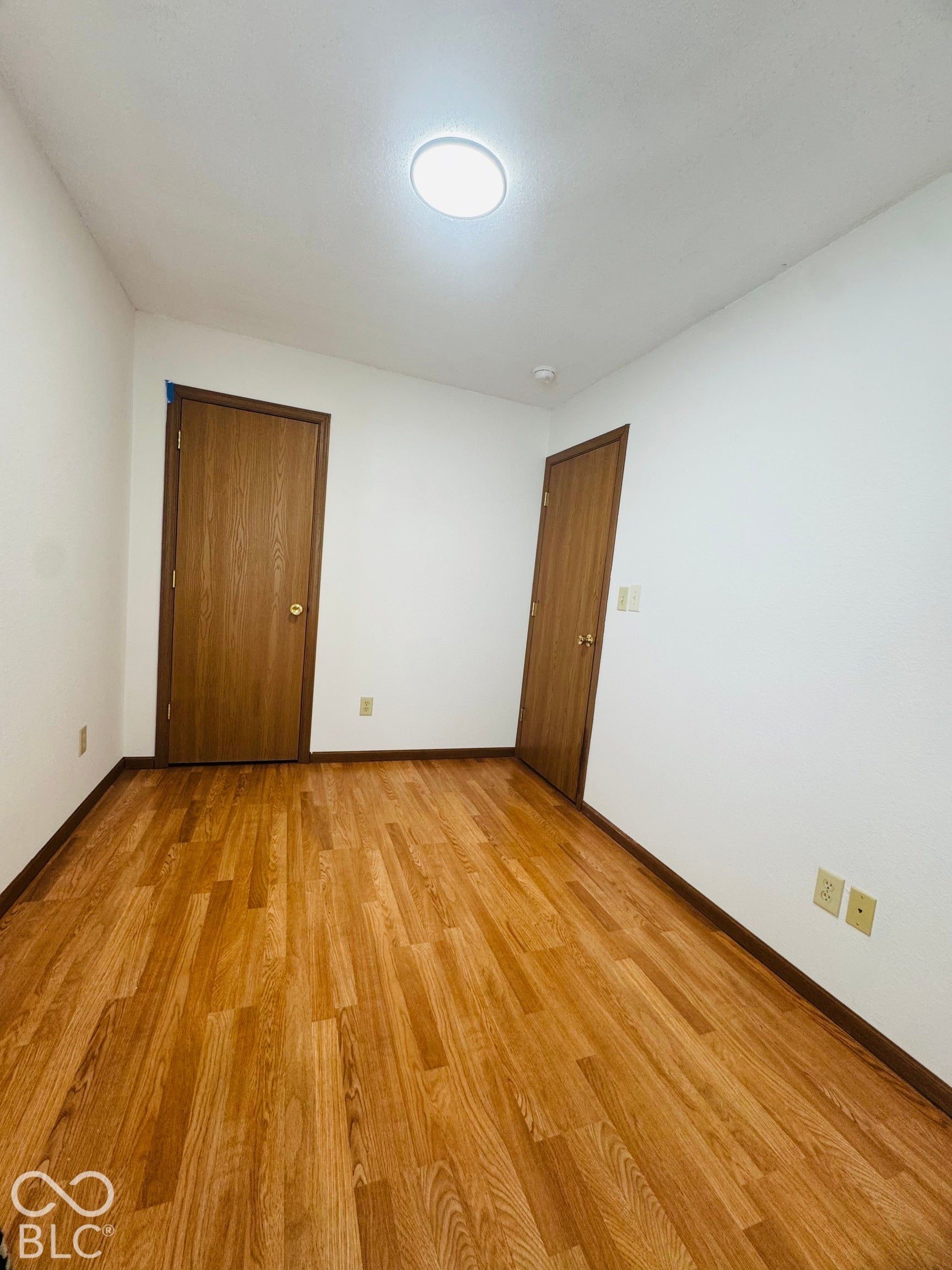 Wood-finish flooring with light-toned walls and dark wood-finish doors