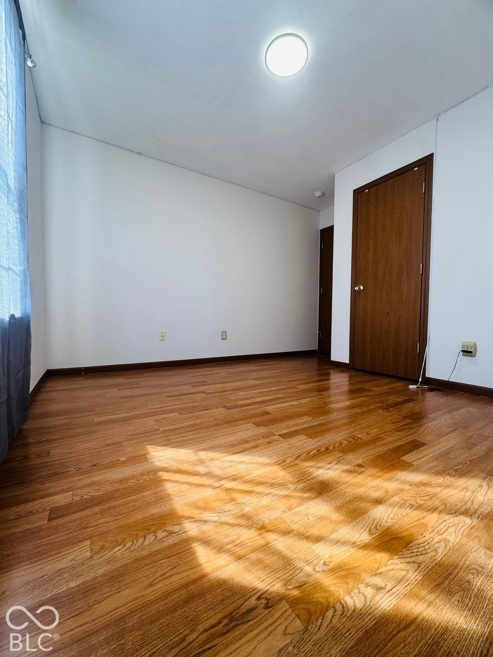 Wood-finish flooring throughout, white walls, and a recessed ceiling light
