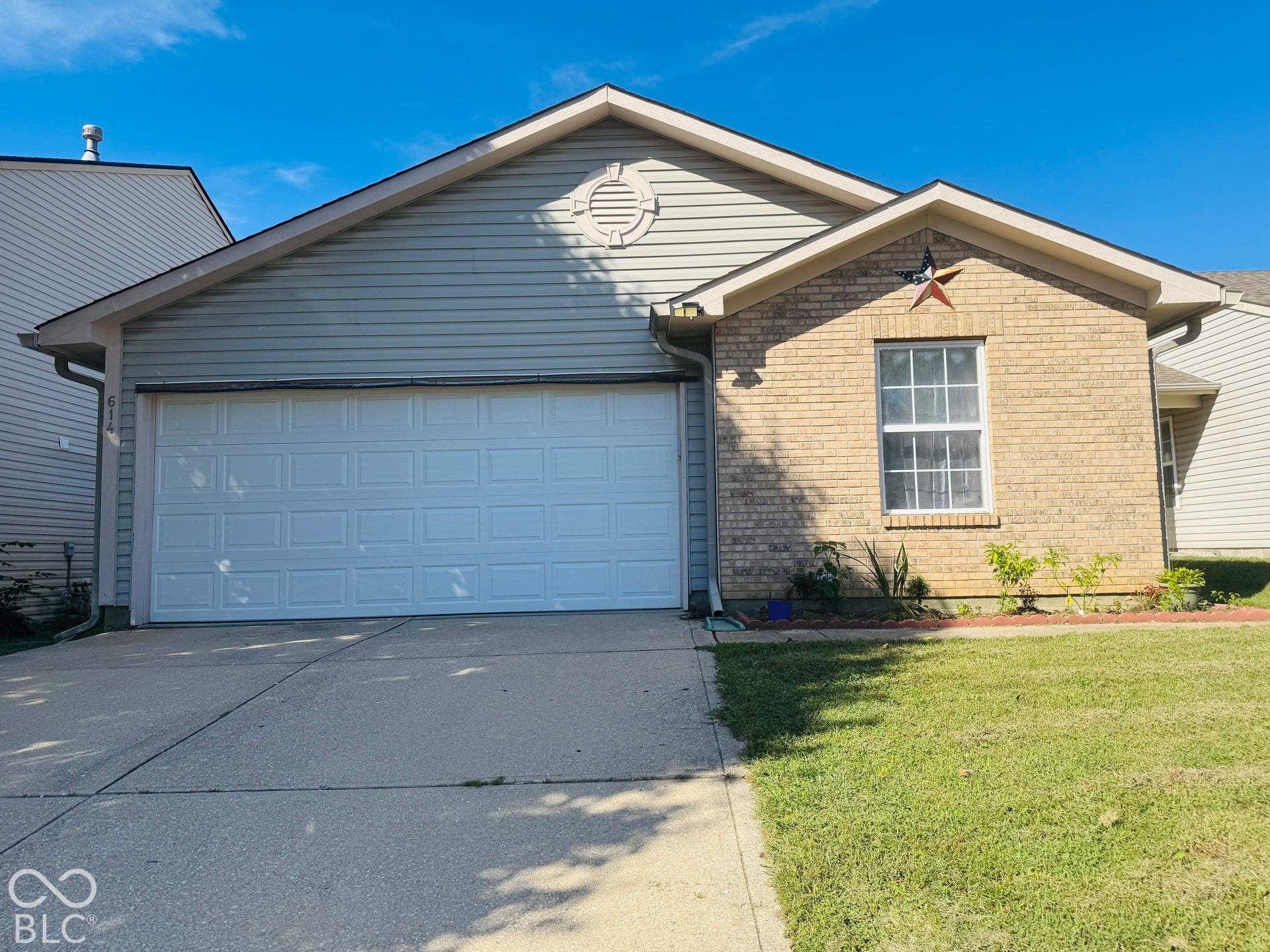 Brick and siding exterior with an attached garage, concrete driveway, and front lawn