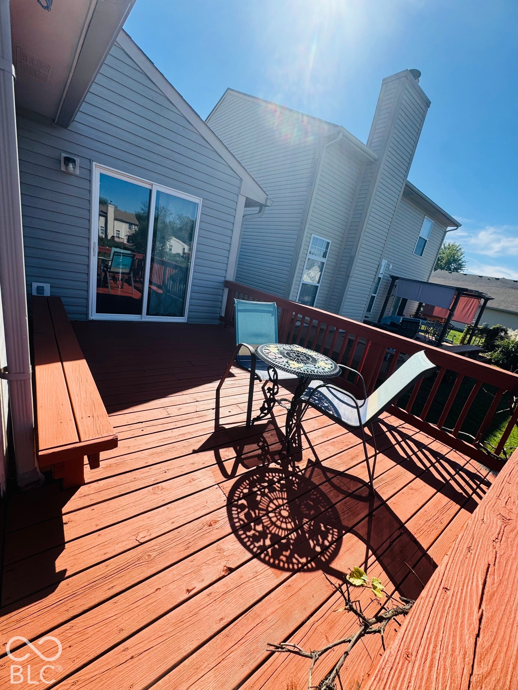 Expansive wooden deck with integrated bench seating, featuring a sliding glass door entry to the interior, and a light-toned exterior siding