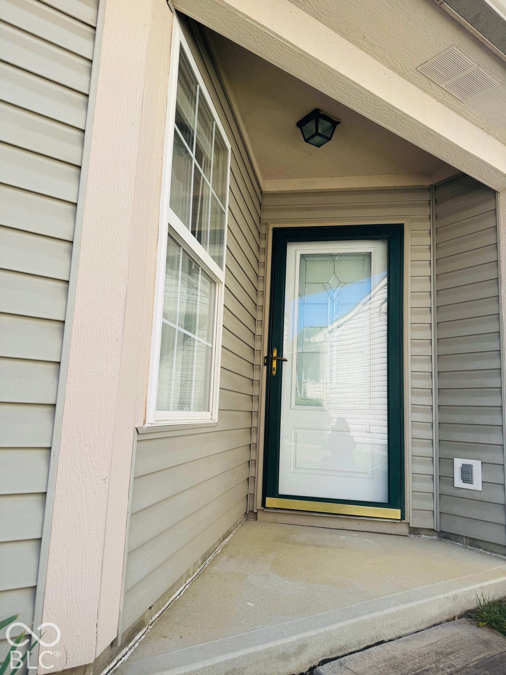 Front entry featuring a storm door, an exterior light fixture, and horizontal siding