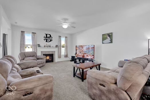 Spacious living area featuring a fireplace with a mantel, vaulted ceiling, and carpeted flooring