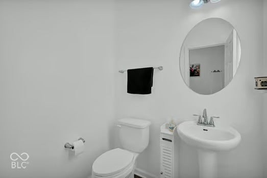 Pedestal sink with chrome fixtures, oval wall mirror, and overhead lighting