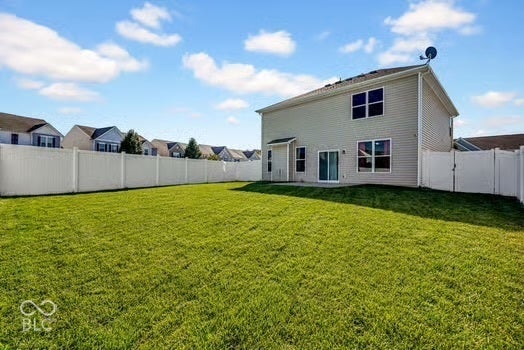 Expansive grassy yard with full vinyl privacy fencing and a sliding glass door