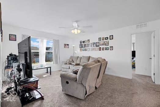 Carpeted living area featuring a ceiling fan with light kit, a window, and a white interior door