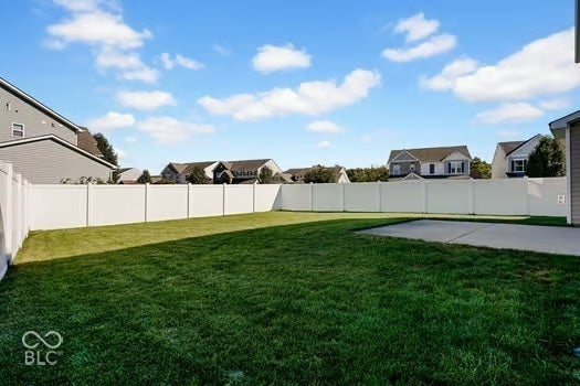 Expansive lawn area, white vinyl privacy fencing, and a concrete patio