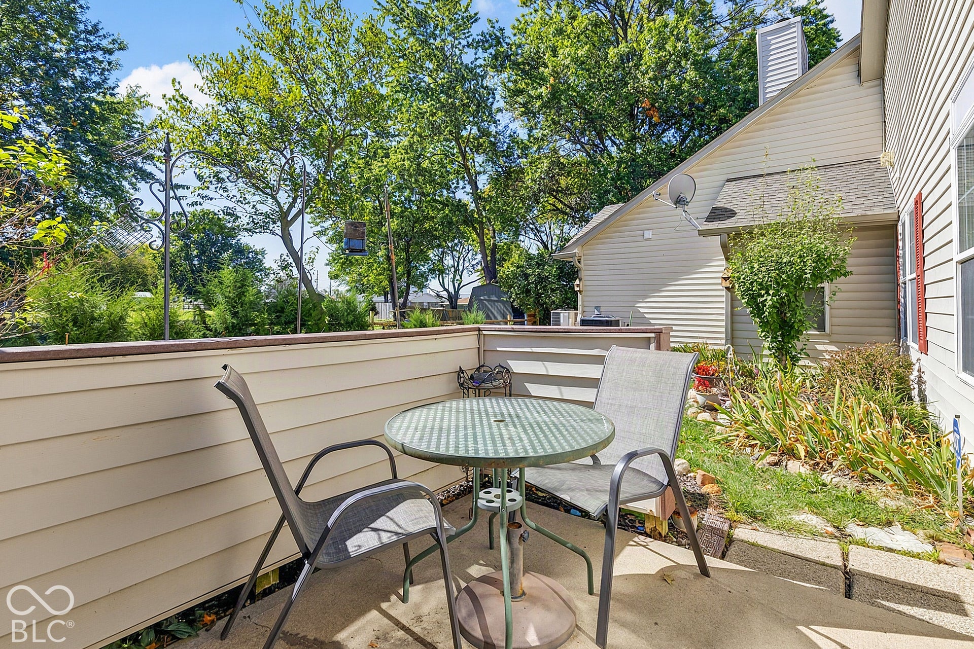 Private patio with concrete flooring, accented by exterior siding and lush perimeter landscaping