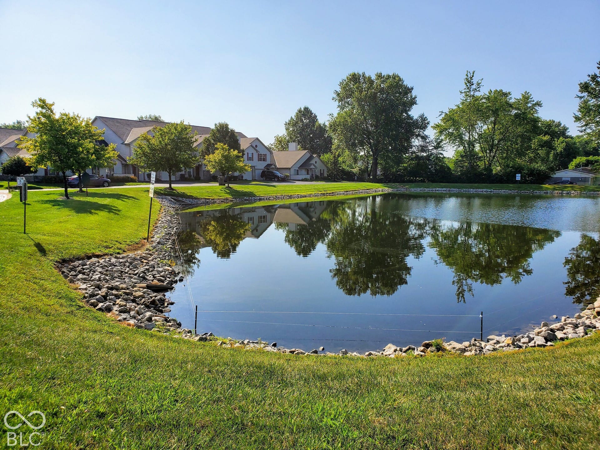 Expansive pond with rocky shoreline and surrounding green lawn