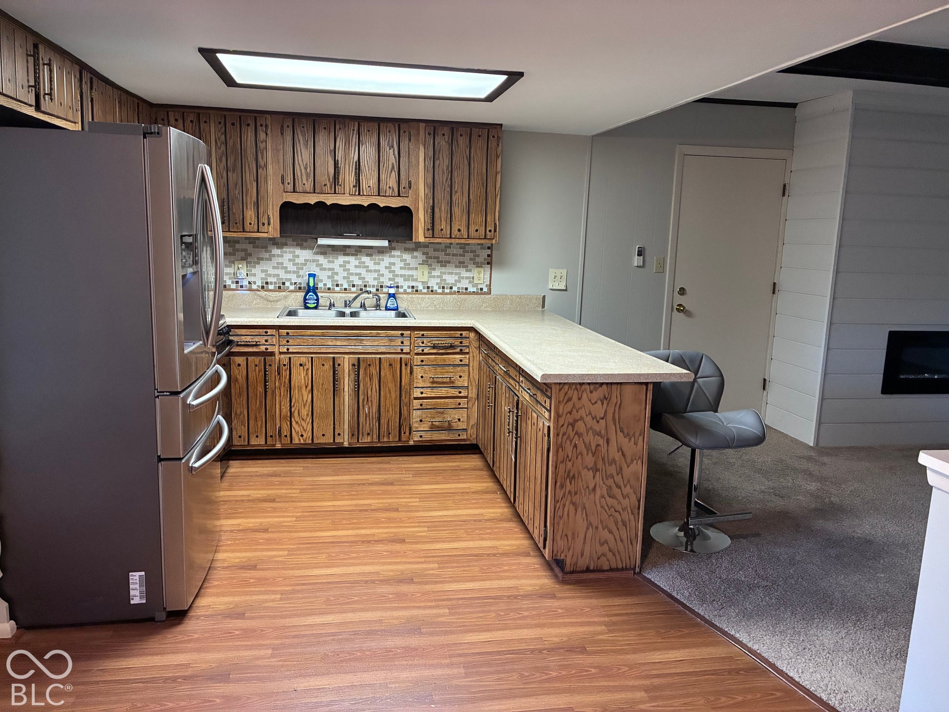 Full kitchen with wood-finish cabinetry, light-colored countertops, and a tiled backsplash