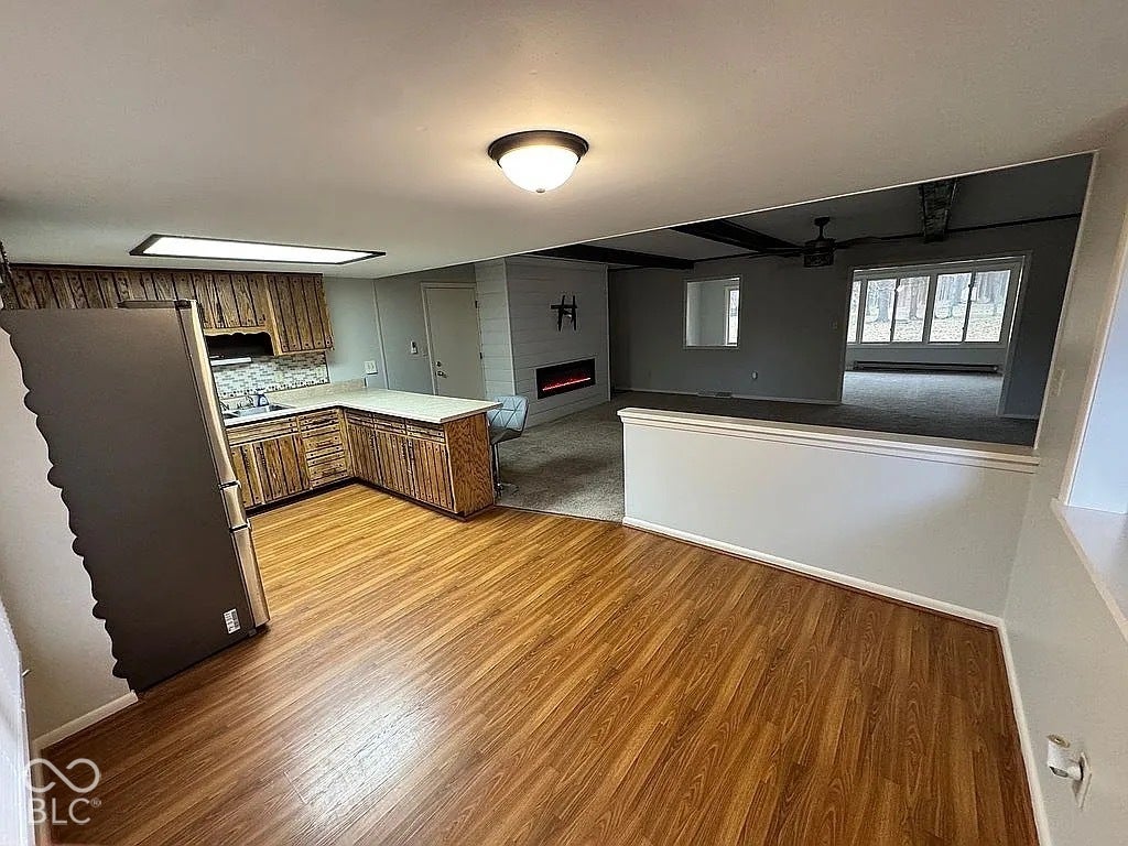 Kitchen with wood-finish cabinetry, light-colored countertops, and mosaic tile backsplash