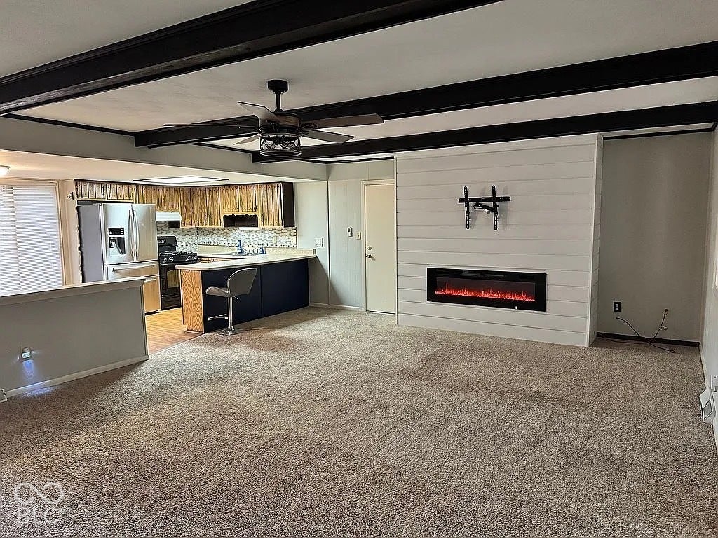 Open concept living space featuring a shiplap accent wall with an electric fireplace