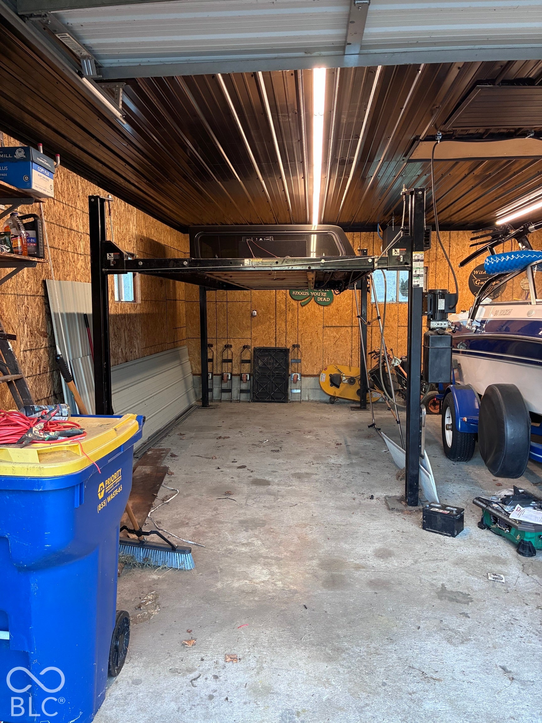 Automotive lift system, corrugated metal ceiling, wood paneling, concrete flooring, fluorescent lighting