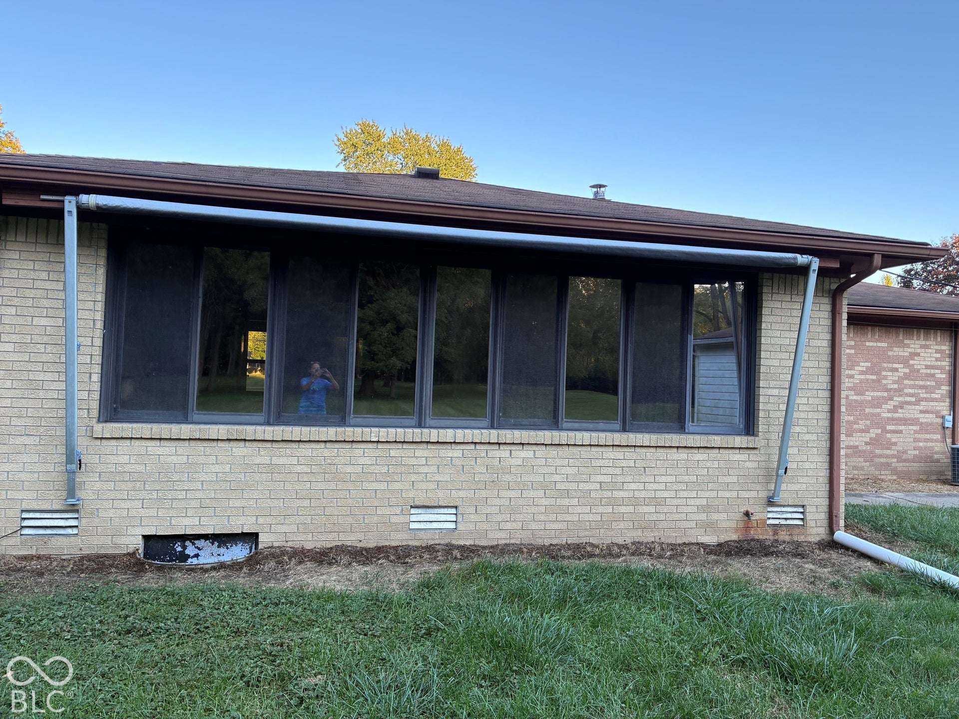 Brick exterior with a brown shingle roof, featuring multiple windows