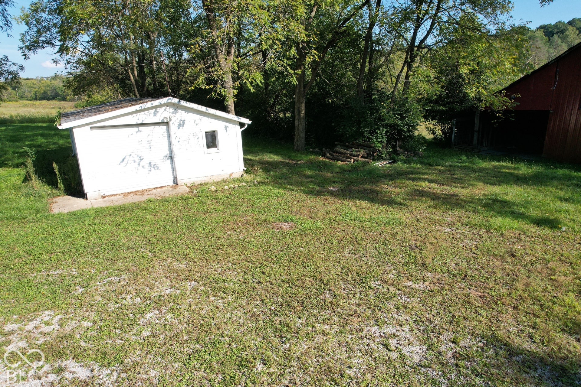 White utility shed with a gable roof and a single window, set on a concrete foundation
