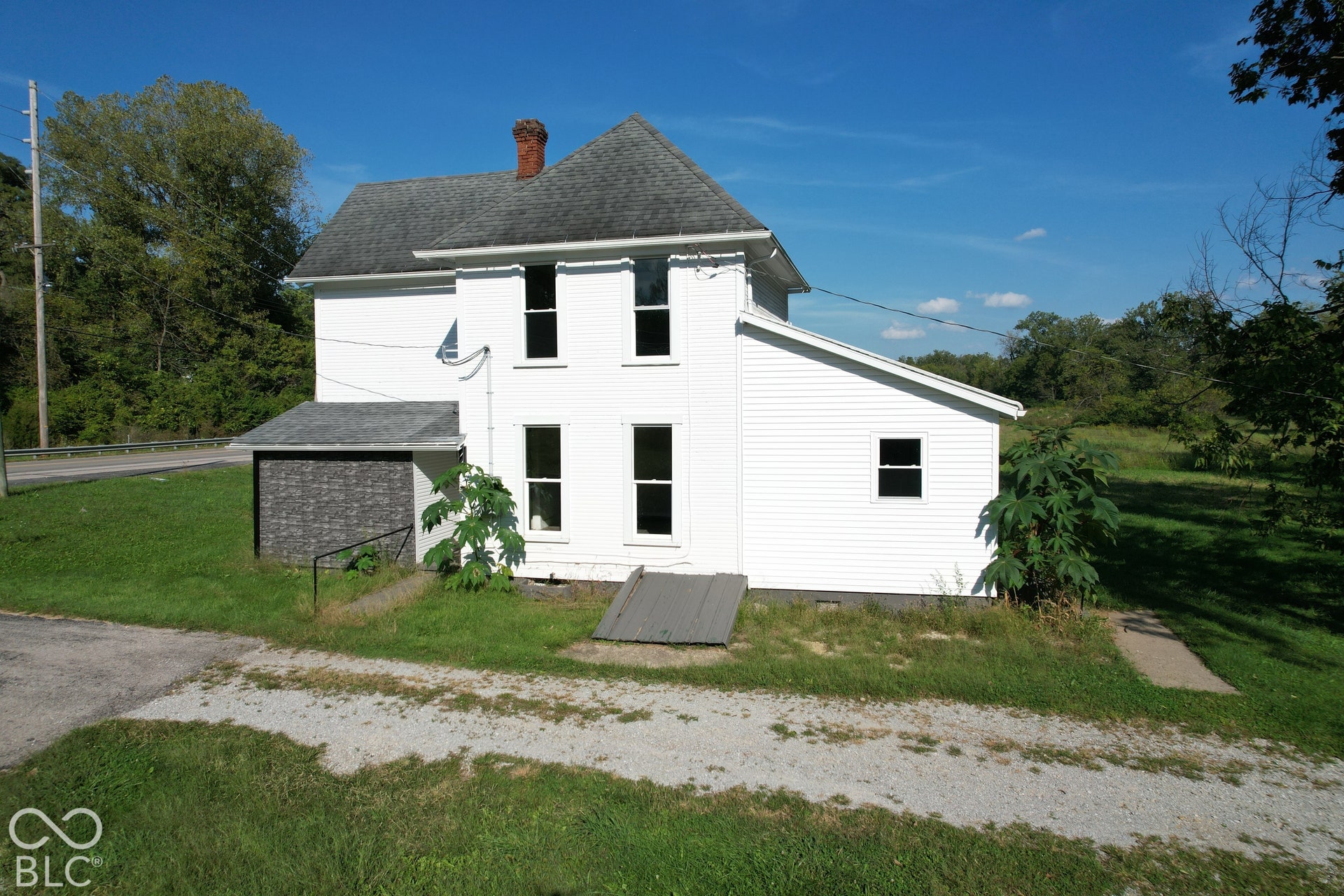 White siding exterior with a dark shingle roof and a brick chimney