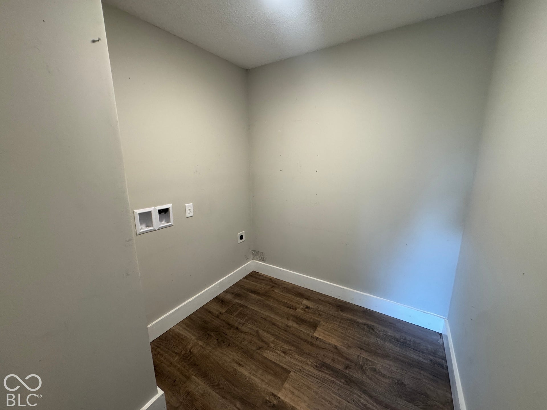 Utility room featuring wood-finish flooring and light-toned walls
