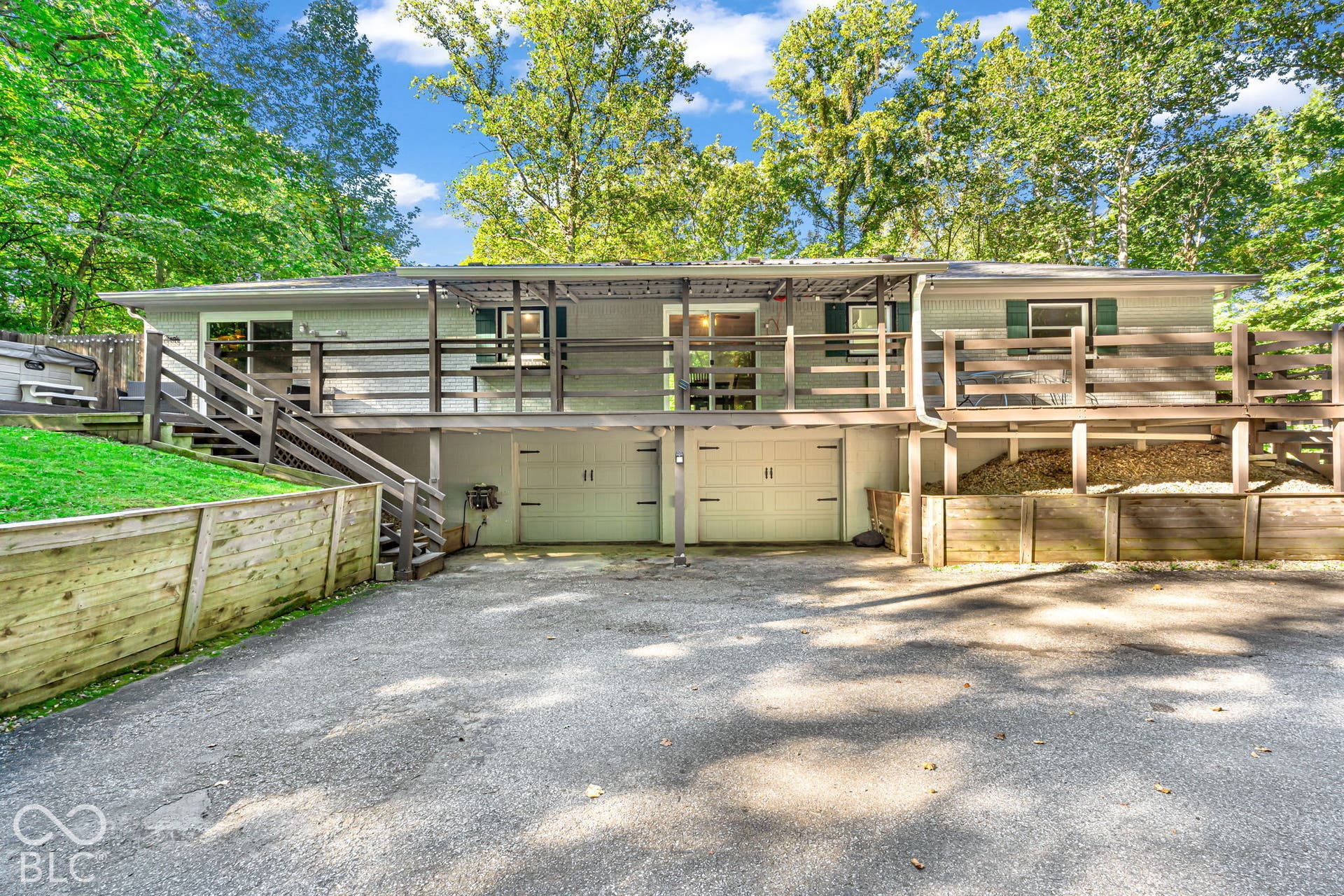 Exterior facade with dual garage doors, expansive multi-level wood deck, and wood retaining walls