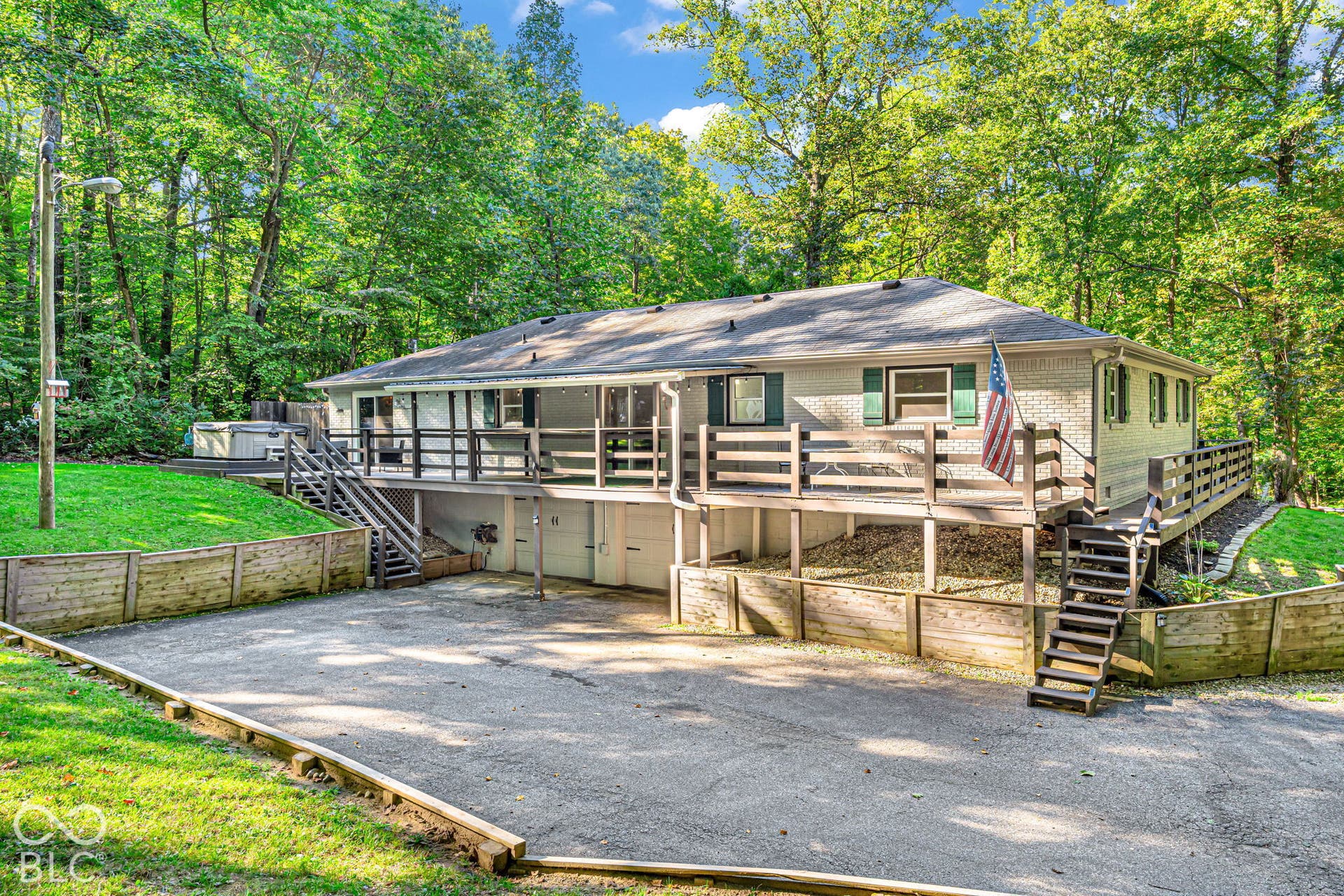 Raised home with a gray exterior, covered porch, and multiple garage doors