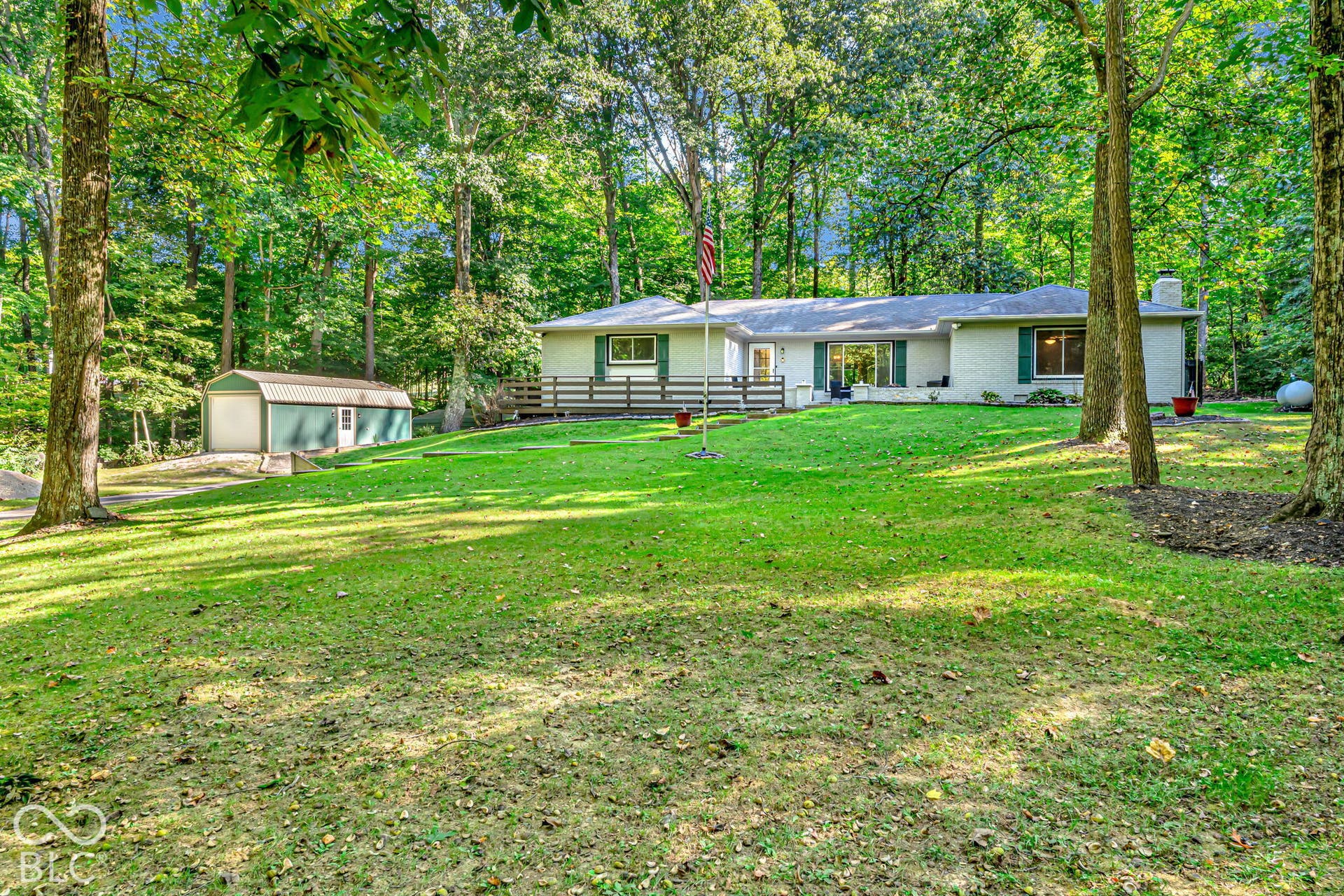 Ranch-style residence with a light-colored exterior, surrounded by mature trees