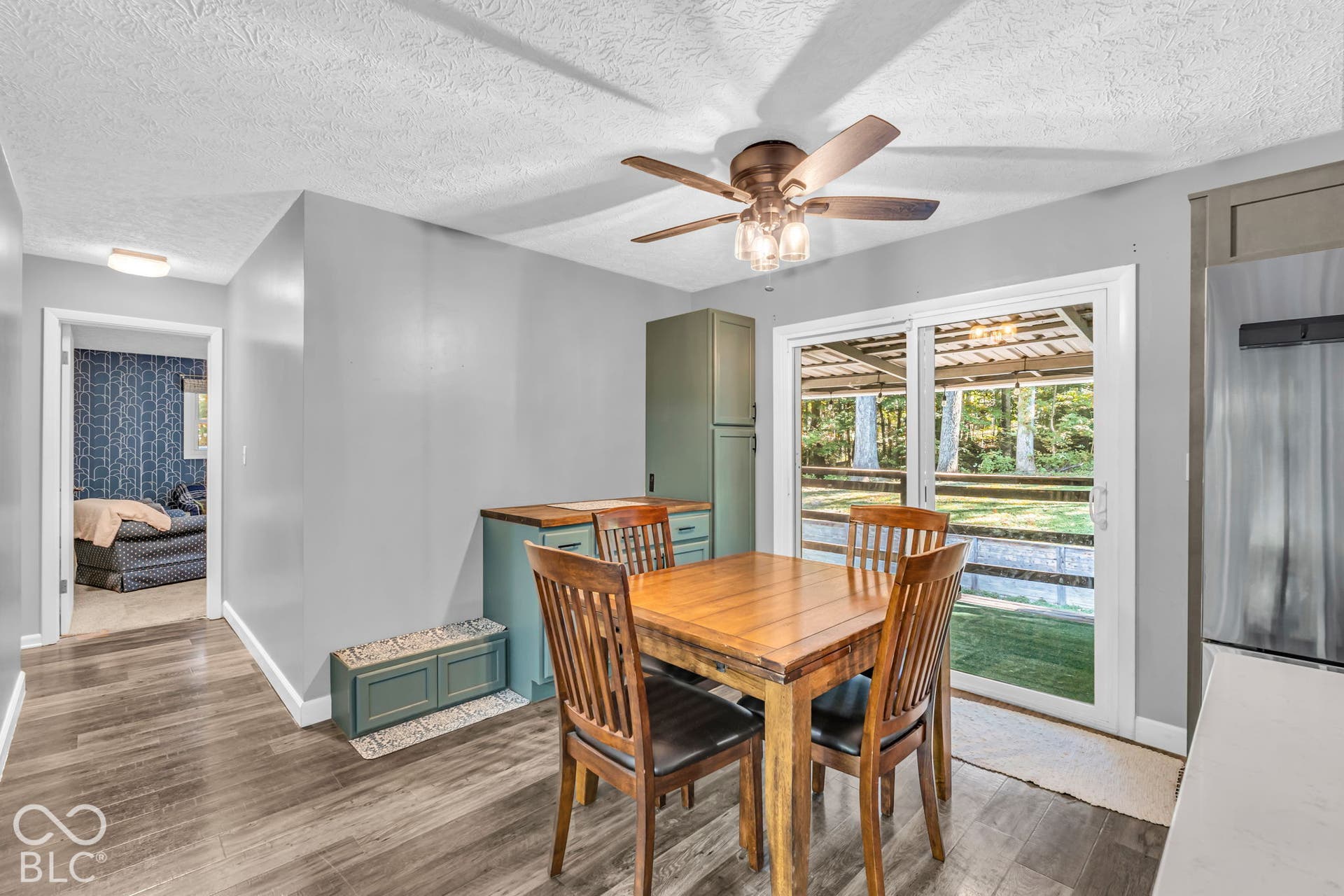Wood-finish flooring, ceiling fan with integrated lighting, built-in cabinetry, and sliding glass door