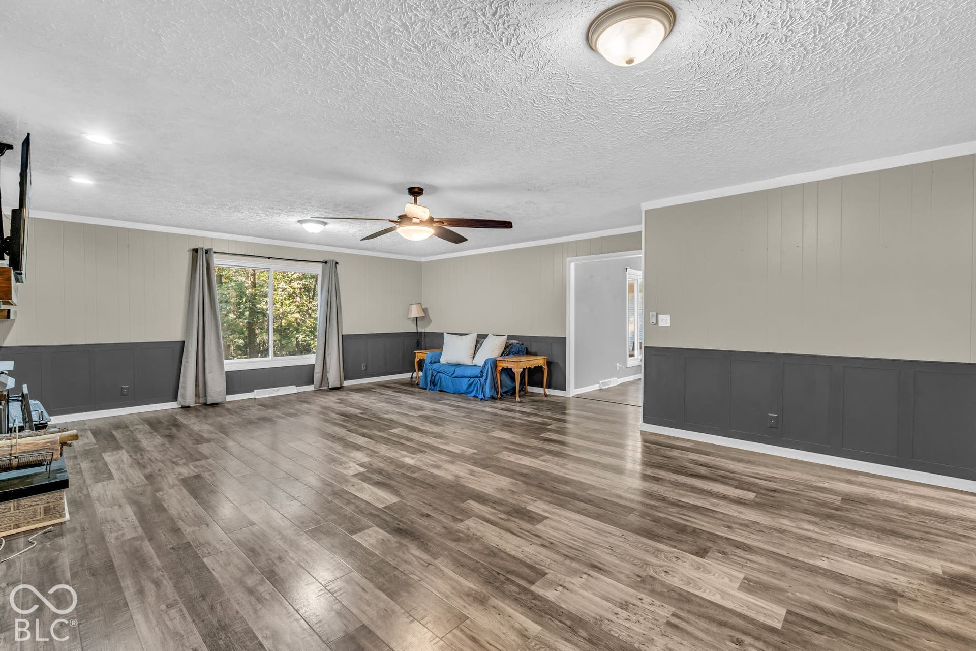 Spacious living area featuring wood-finish flooring, a ceiling fan, recessed lighting, and a large window
