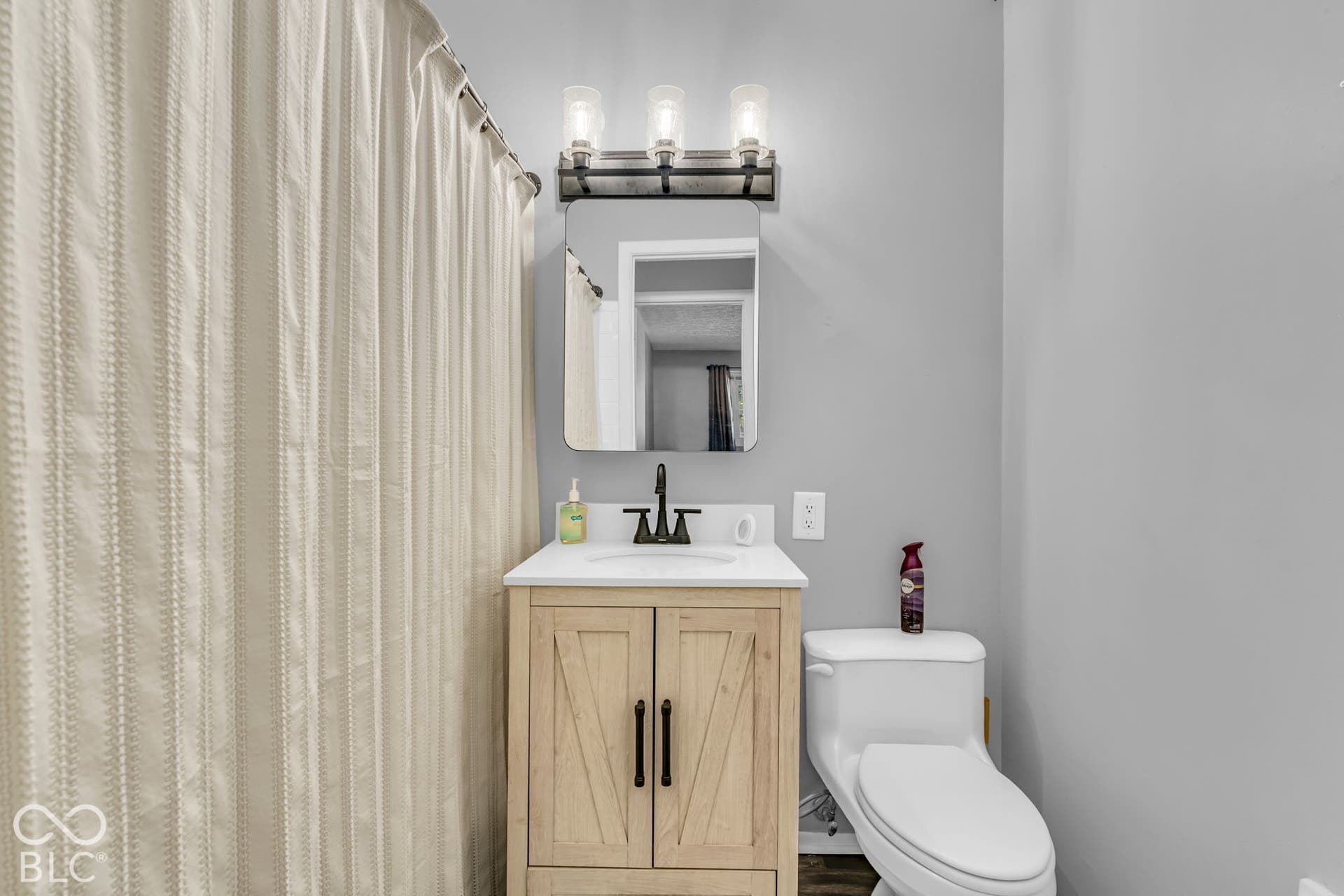 Vanity with a white countertop and a rectangular undermount sink, black faucet, and a wall-mounted mirror
