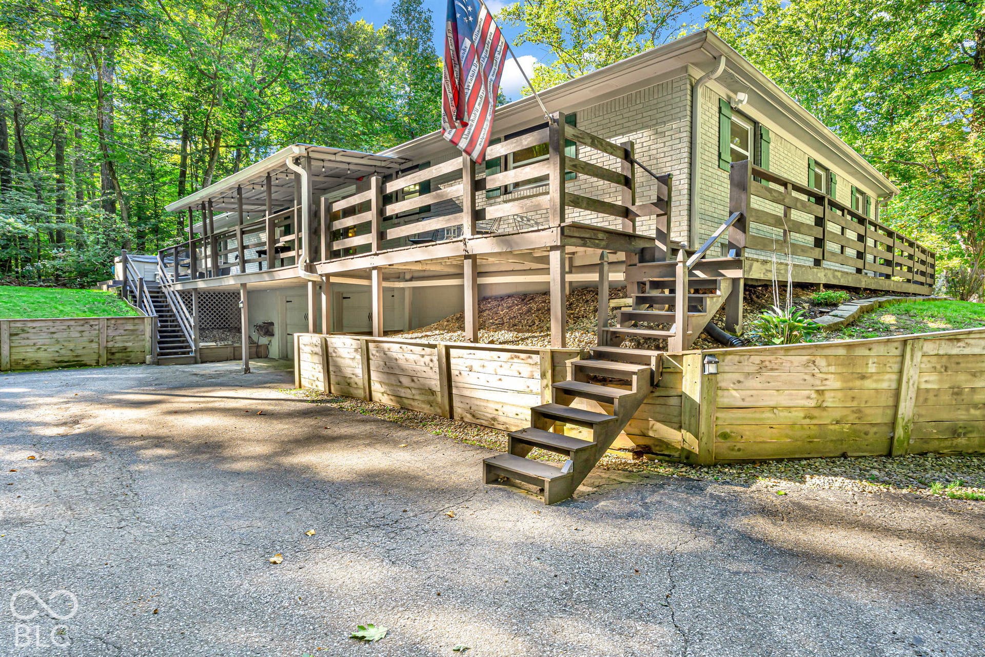 Exterior featuring a multi-level deck with wooden railings, light brick siding, and green window shutters