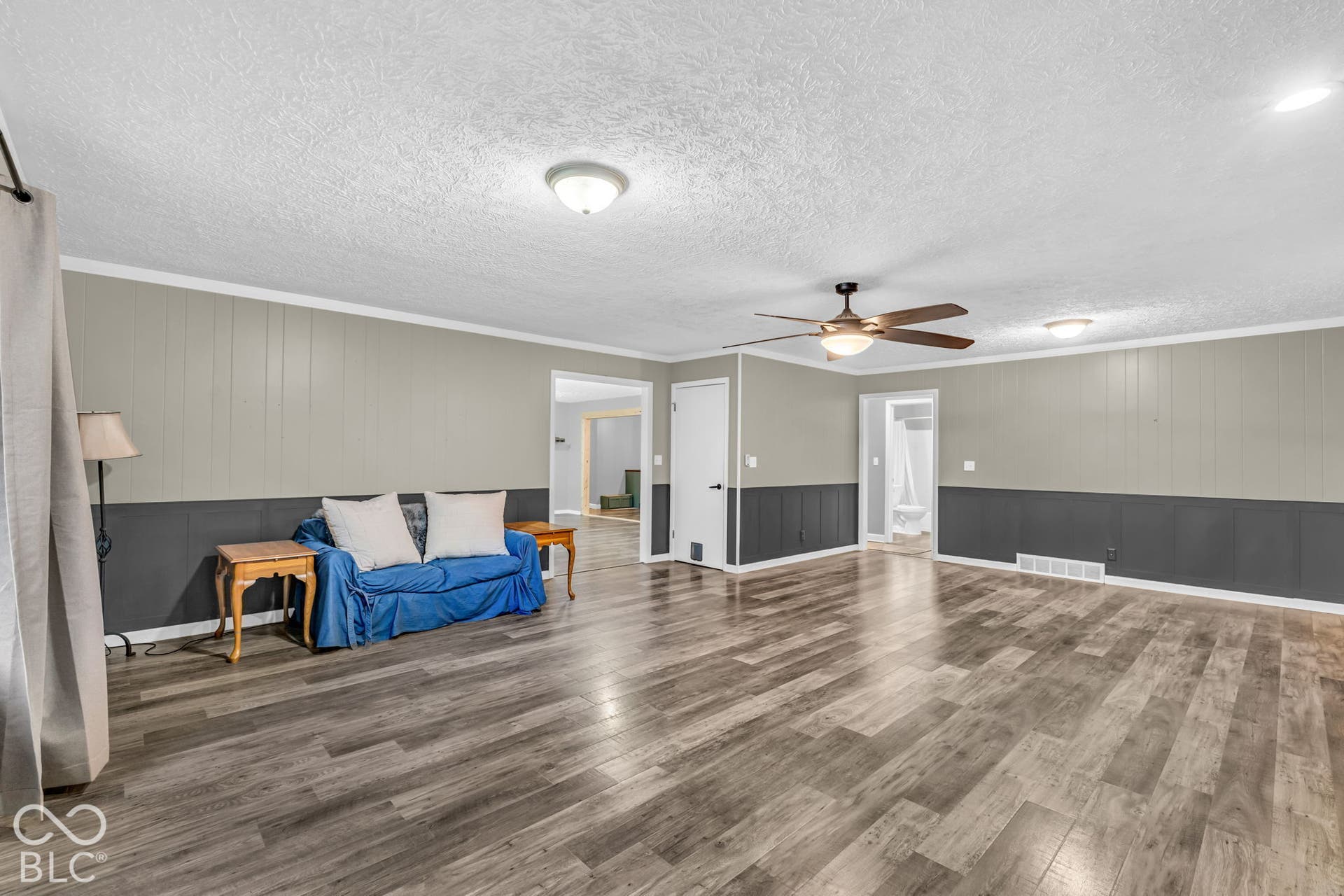 Wood-finish flooring, two-tone wall paneling, ceiling fan, and recessed lighting