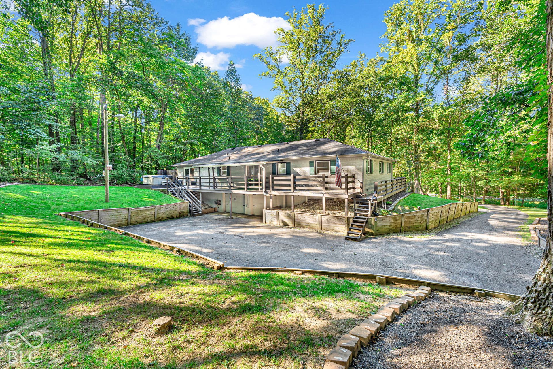 Ranch-style exterior with a raised deck, multi-level stairs, and a gravel driveway
