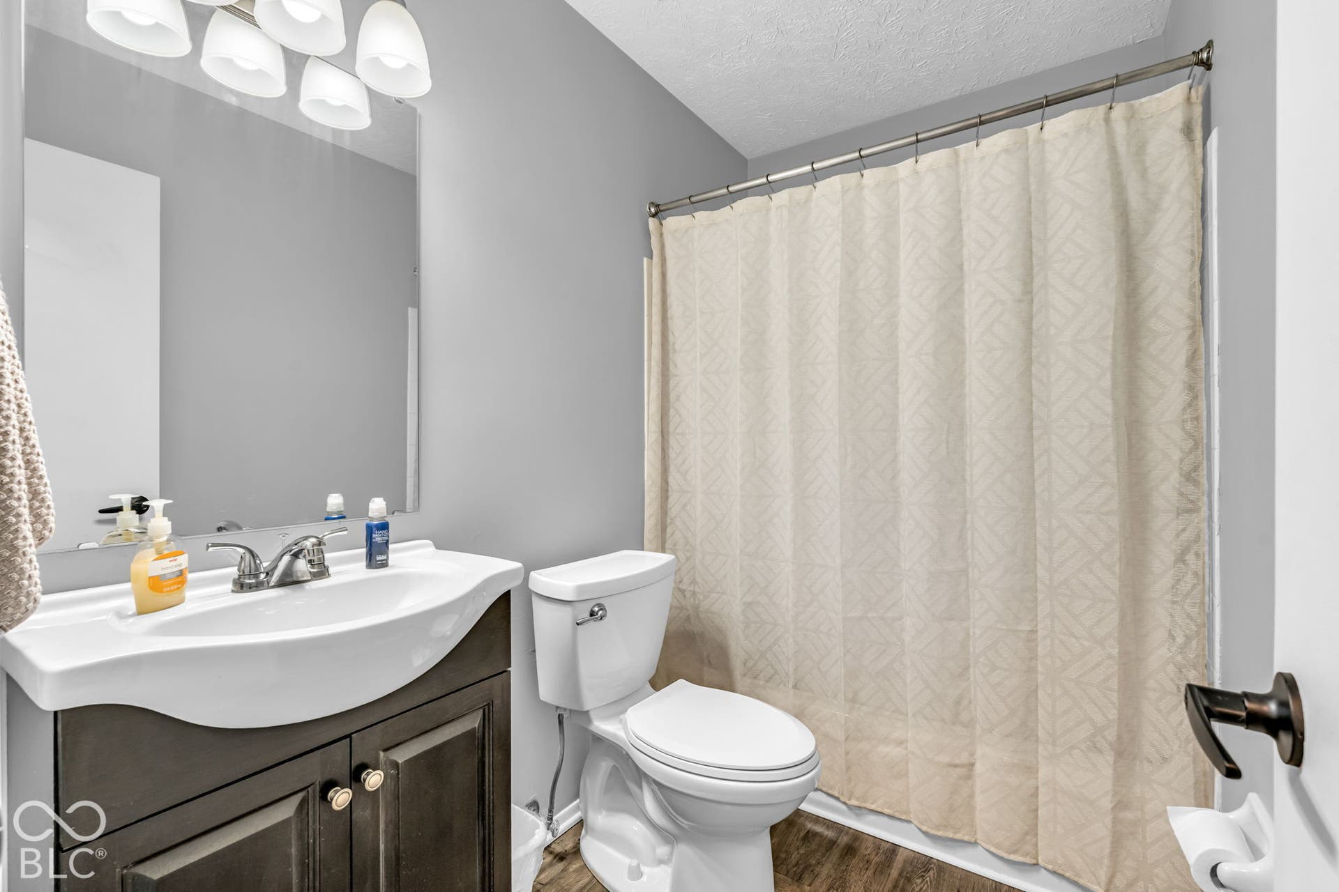 White vanity with integrated sink, chrome faucet, and dark wood-finish cabinetry