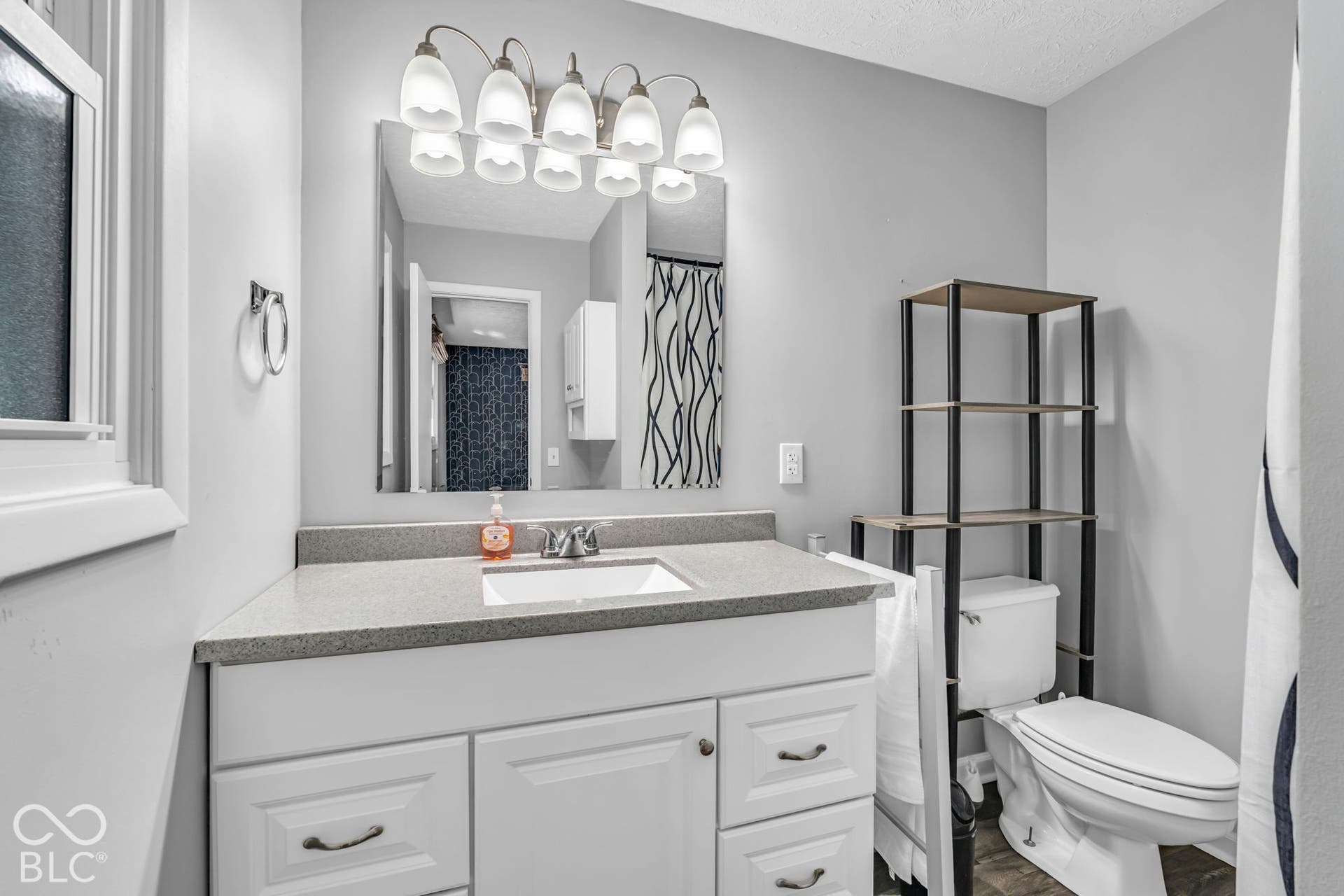 White vanity with brushed nickel hardware, integrated sink, and a speckled gray countertop