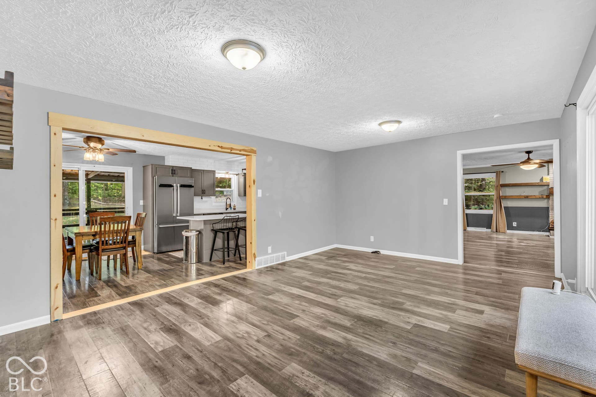 Wood-finish flooring throughout, with a framed doorway leading to the kitchen featuring stainless steel appliances and a breakfast bar