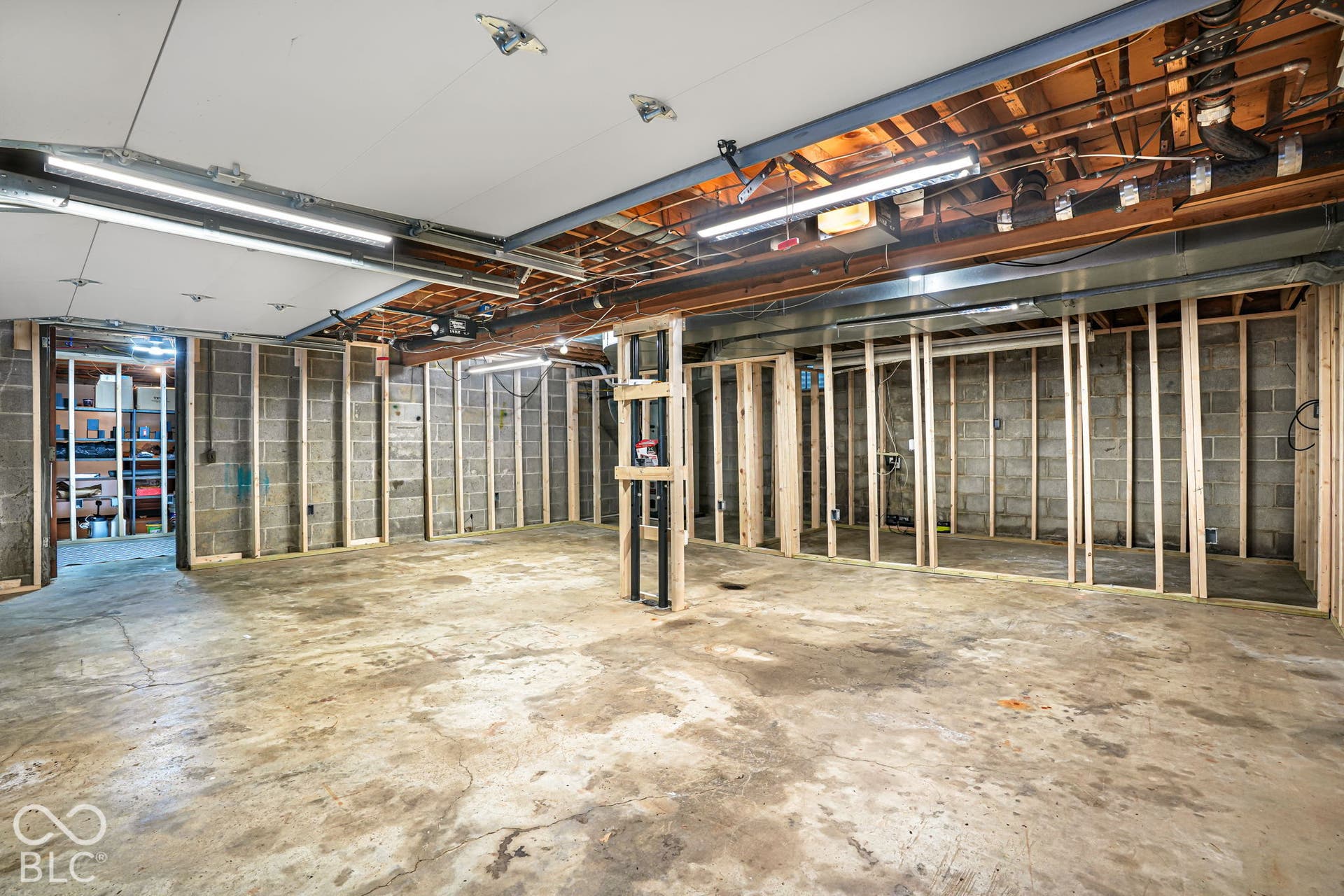Unfinished lower level with concrete flooring, framed interior walls, exposed ceiling joists, and block walls