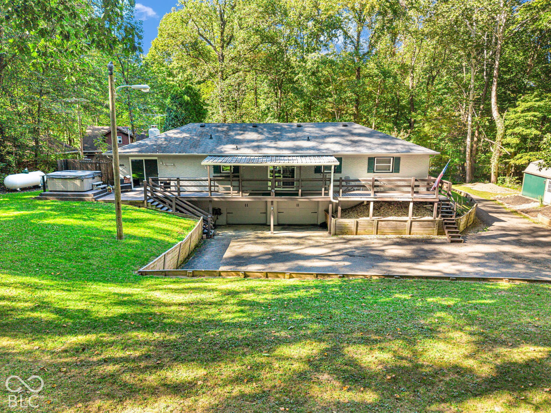Expansive back deck, multi-level wood decking, sliding glass door access, lower-level garage, and separate storage shed