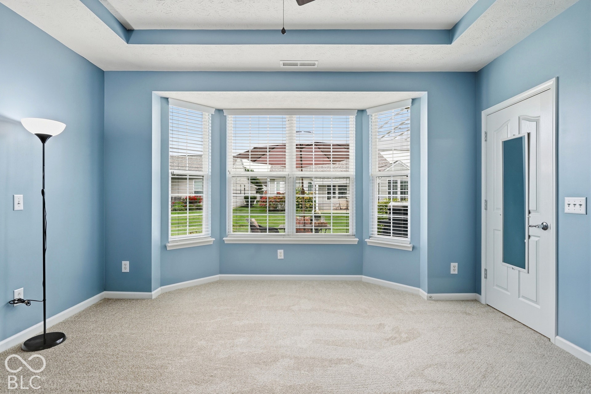 The primary bedroom is located at the back of the house with a bay window & tray ceiling.