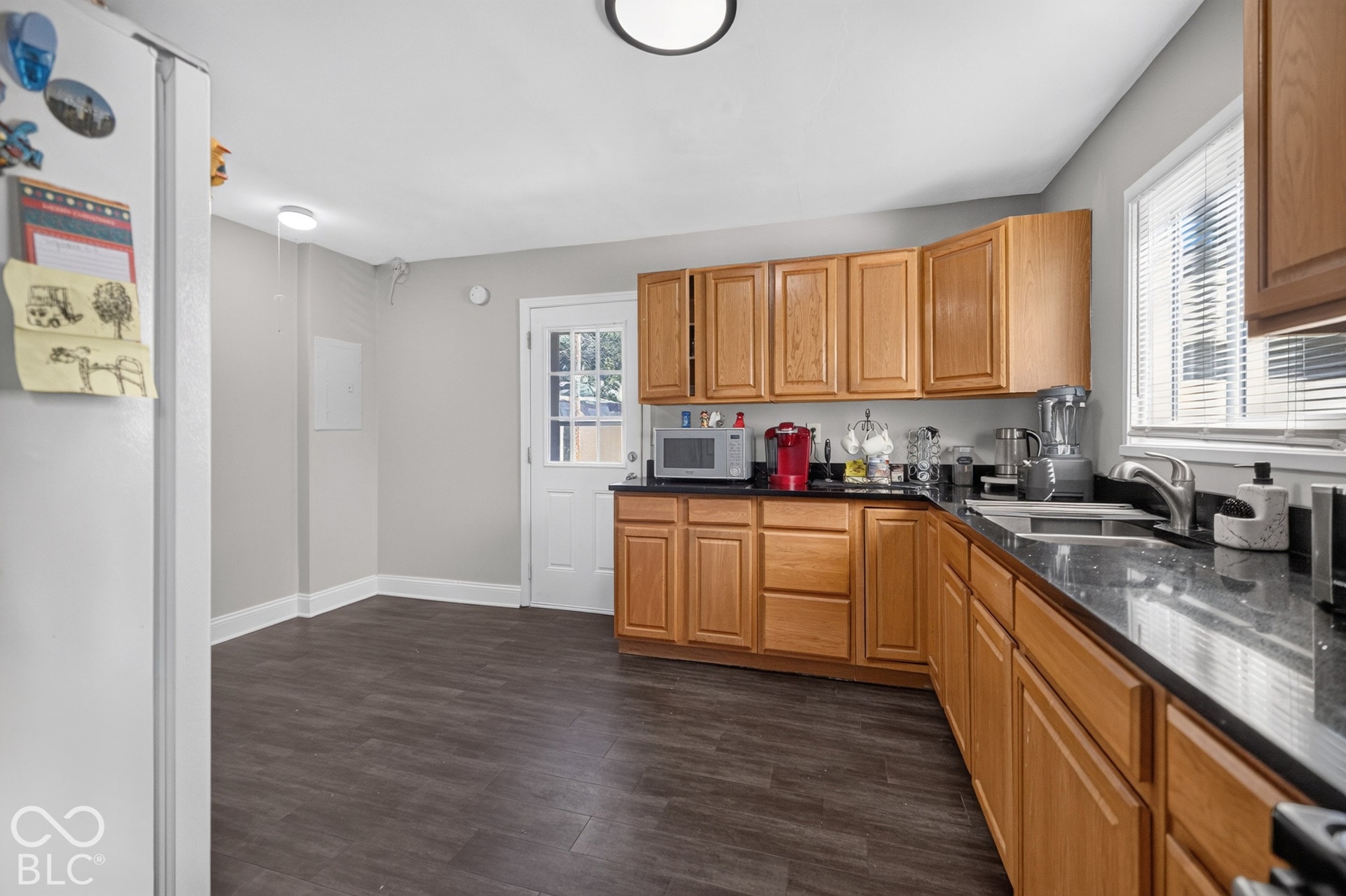 3241 Winton Avenue, Indianapolis, IN 46224 Kitchen featuring wood-finish flooring, natural wood cabinetry, dark countertops, and a stainless steel sink
