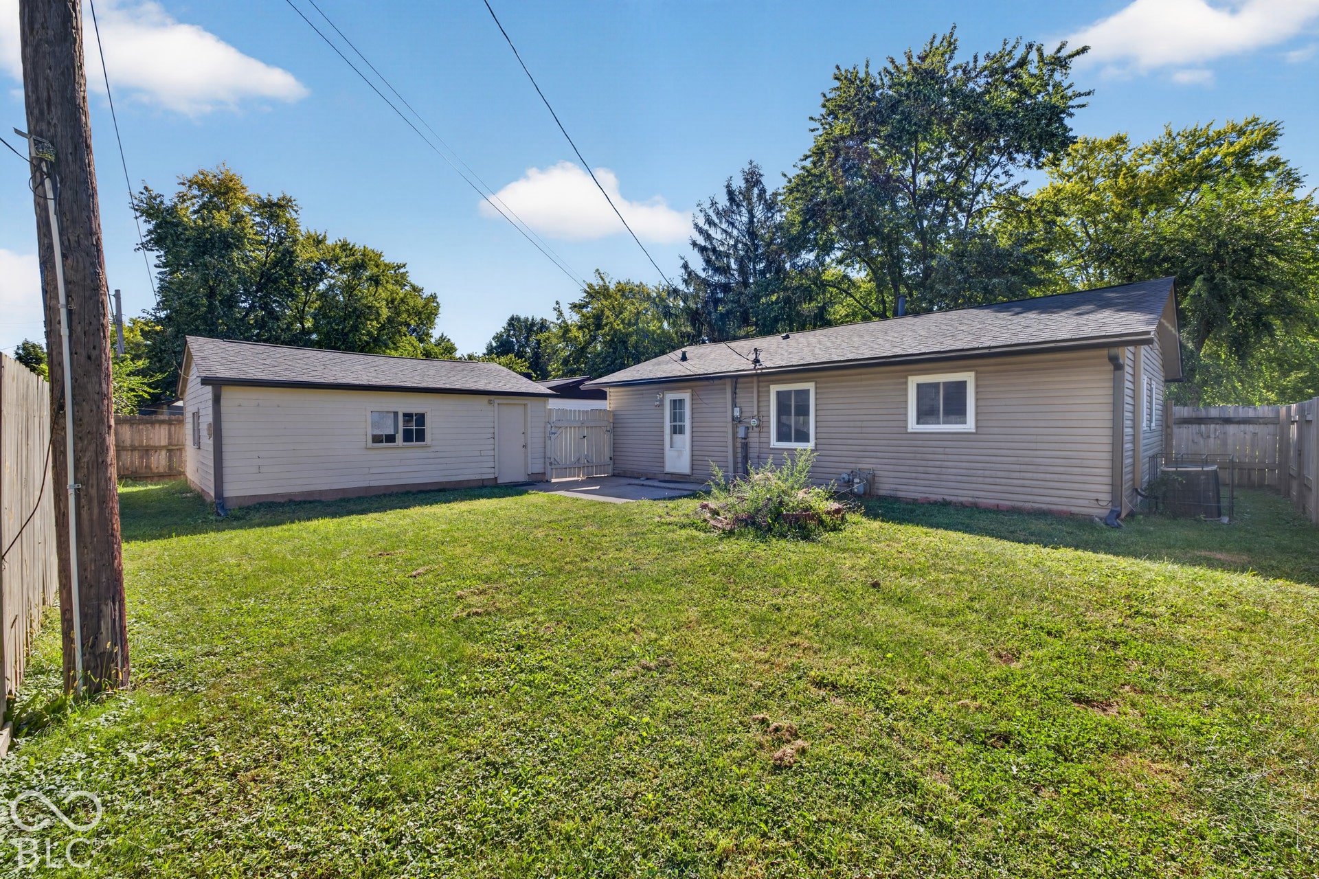3241 Winton Avenue, Indianapolis, IN 46224 Expansive grassy yard with wood fencing, a detached auxiliary structure, and a rear patio